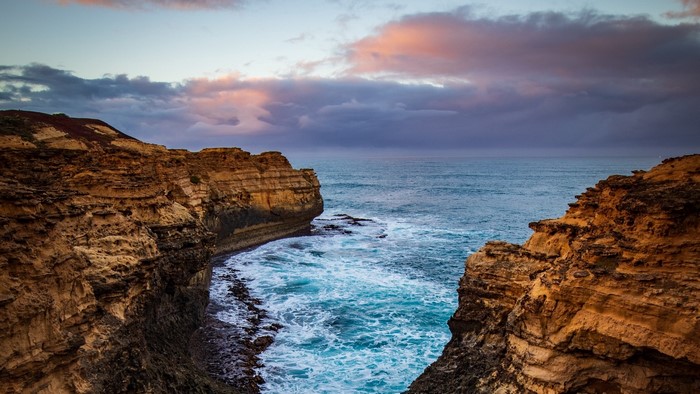 Rocky coastline with ocean waves at sunset
