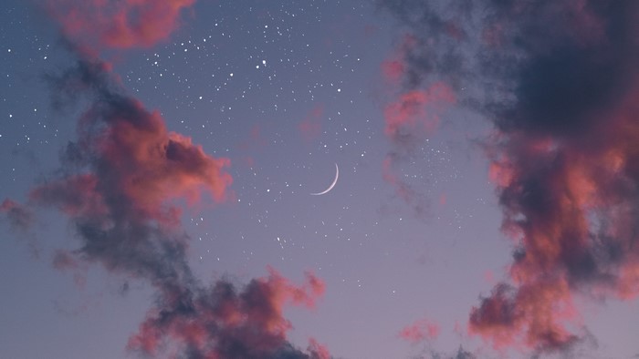 Crescent moon in a starry sky with pink clouds