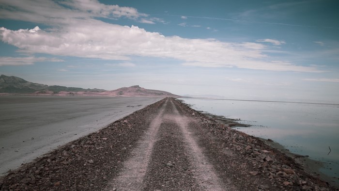 Dirt road along a salt flat and body of water