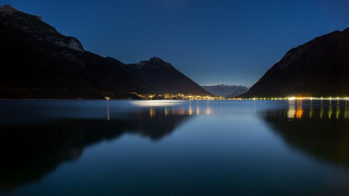 Lake and Mountains at Night with Town Lights