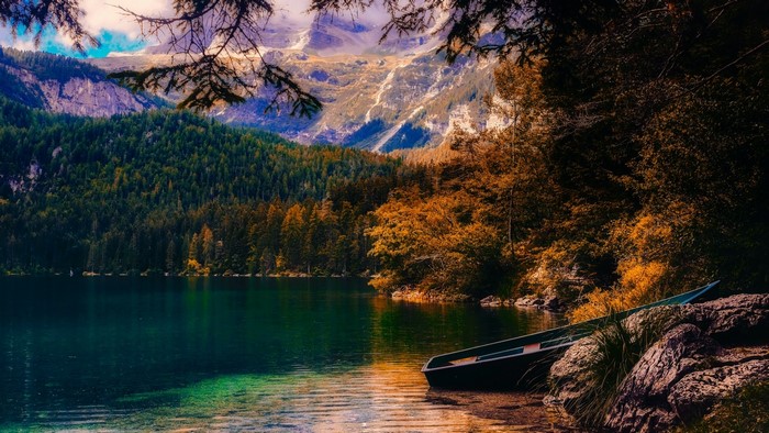 Boat on a lake with mountains and autumn trees