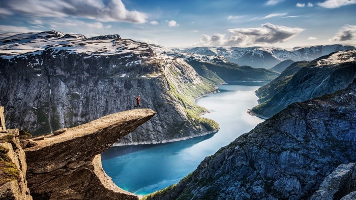 Person on Trolltunga rock overlooking fjord in Norway