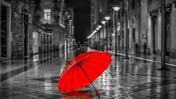Red umbrella on a wet street at night