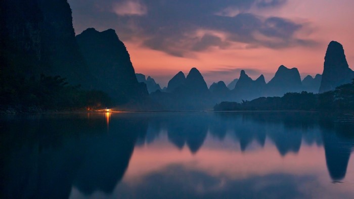 Karst mountains at sunset reflected in a river