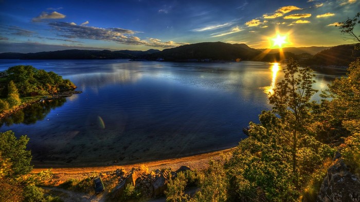 Sunset over a calm lake with trees and mountains