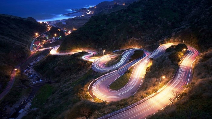 Winding mountain road at night with light trails