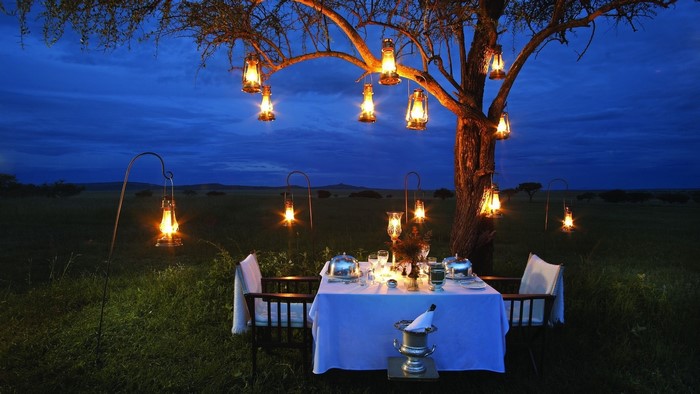Romantic dinner under lanterns in the savanna at dusk