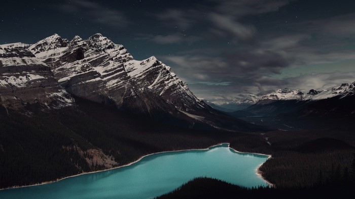Snow-capped mountains and turquoise lake at night