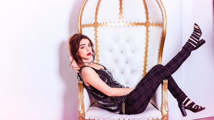 Adelaide Kane sitting on a throne chair