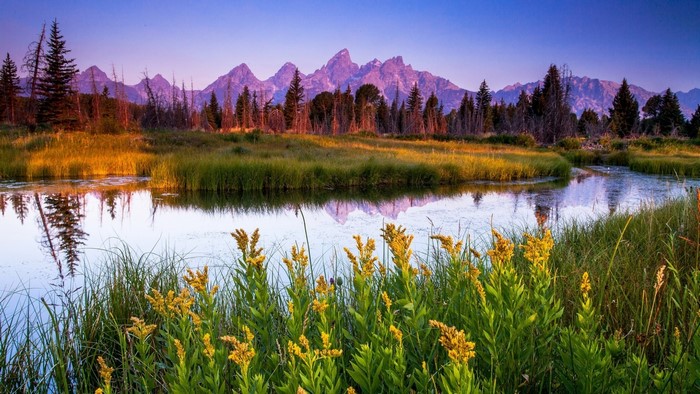 Mountain range reflected in a calm river at sunrise