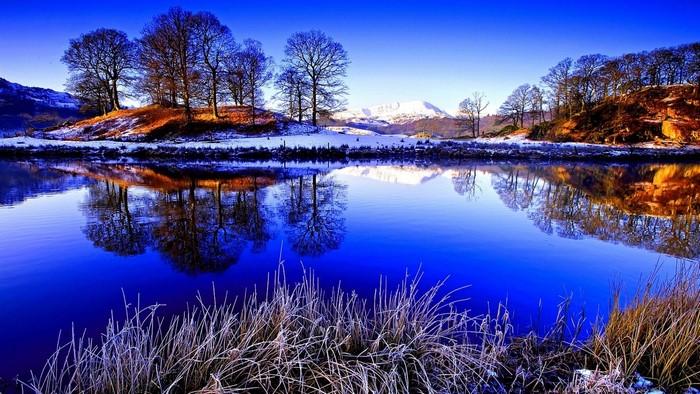 Blue lake with snow-covered mountains and trees