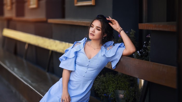Model in a blue dress sitting on a bench