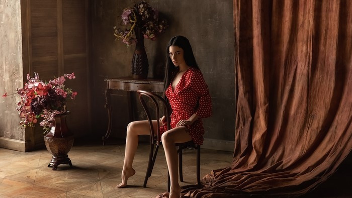 Model in a red polka dot dress sitting on a chair