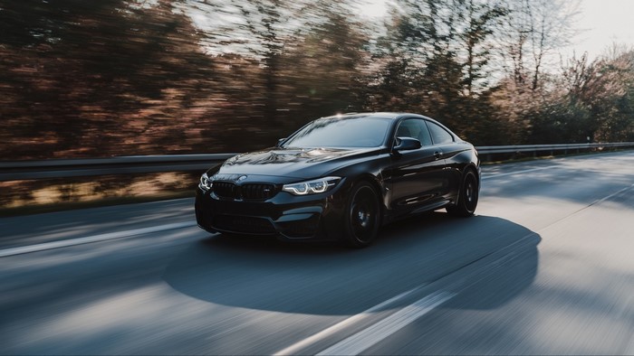 Black BMW M4 Coupe driving on a road
