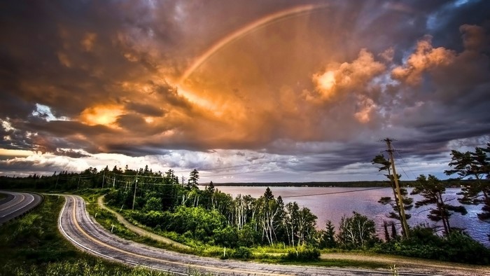 Rainbow over a winding road and a lake