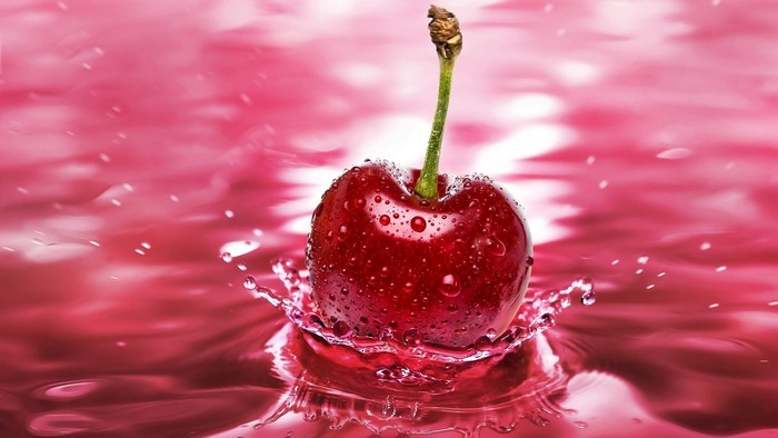 Cherry splashing in pink liquid