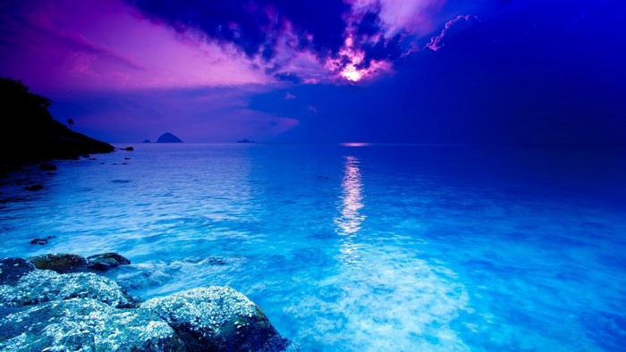 Blue sea with purple clouds and rocky shore