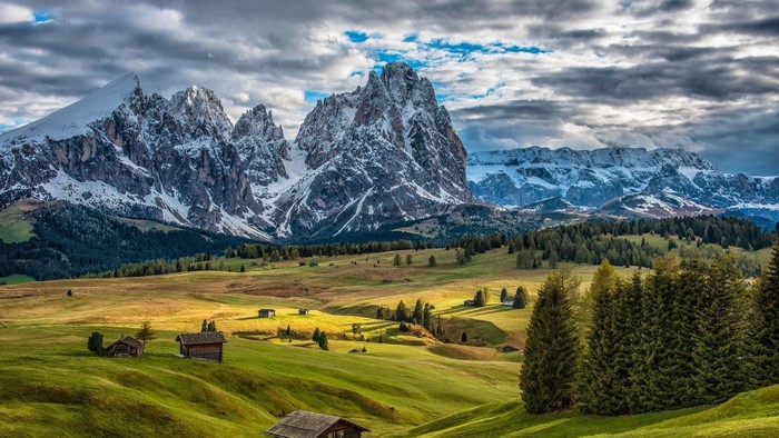 Snow-capped mountains and green meadows with buildings