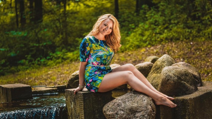 Woman sitting on rocks by a stream