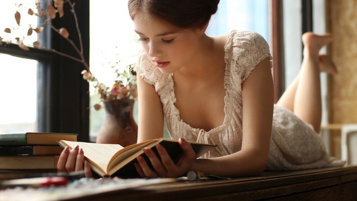 Girl reading a book by the window