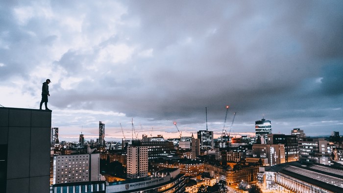 Person standing on a rooftop overlooking a city at dusk