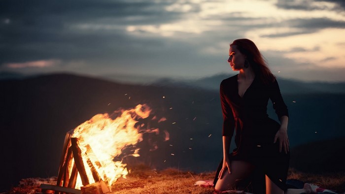 Girl by a campfire in the mountains