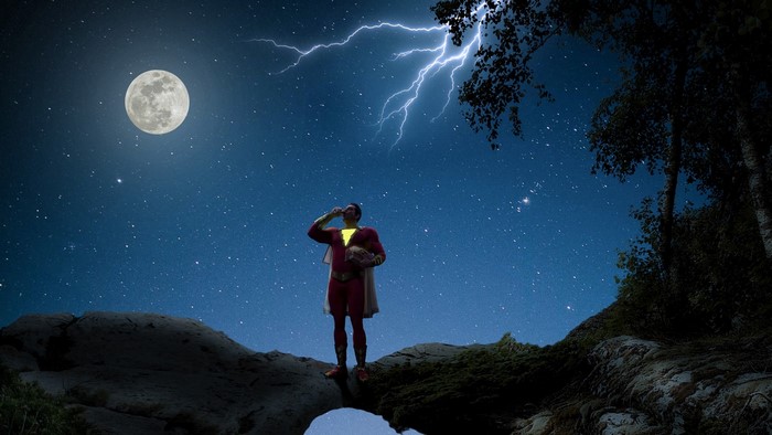 Shazam standing on a rock under a starry night sky with lightning