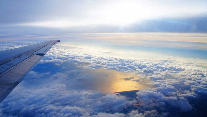 Airplane wing over clouds and ocean
