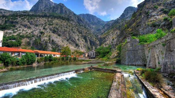 River flowing through a valley with mountains and old stone walls
