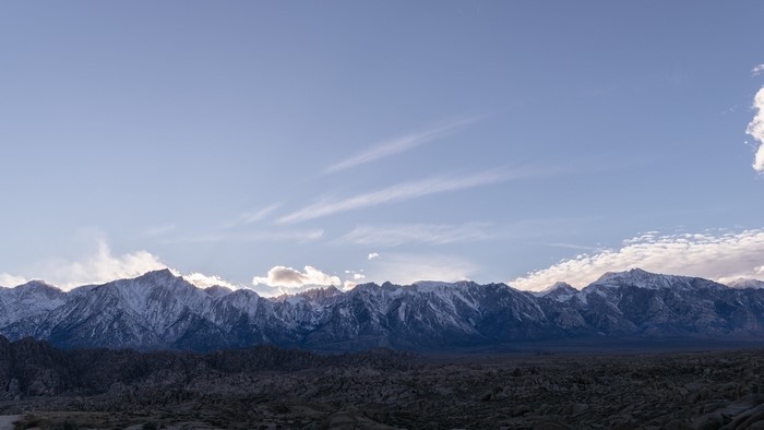 Snow-capped mountains under a pale blue sky