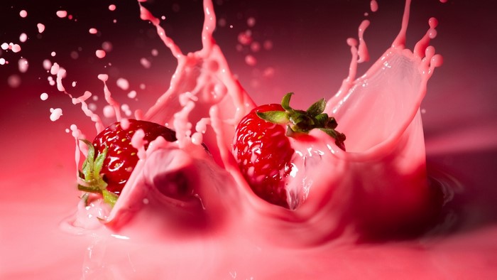 Strawberries splashing into pink milk