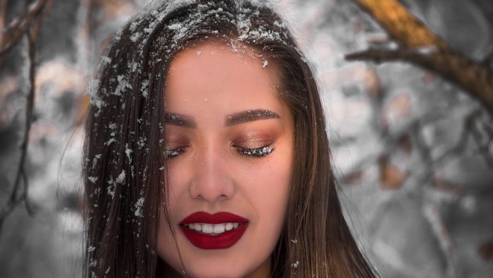 Woman with snow on eyelashes and red lipstick