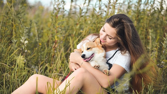 Girl hugging a corgi dog in a field