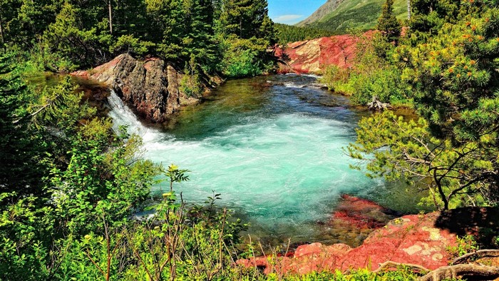 Turquoise river flowing through a forest with red rocks