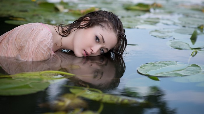 Woman in pink dress in water with lily pads