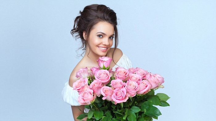 Young woman holding a bouquet of pink roses