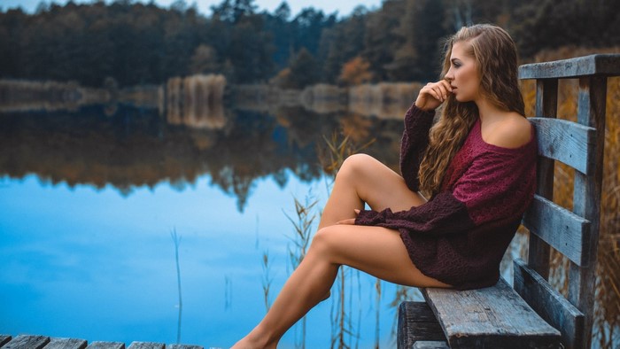 Woman sitting on a wooden bench by a lake