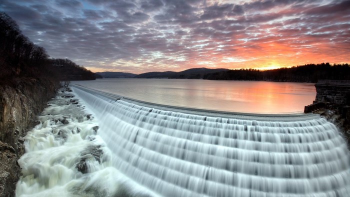 Waterfall cascading over a dam at sunset