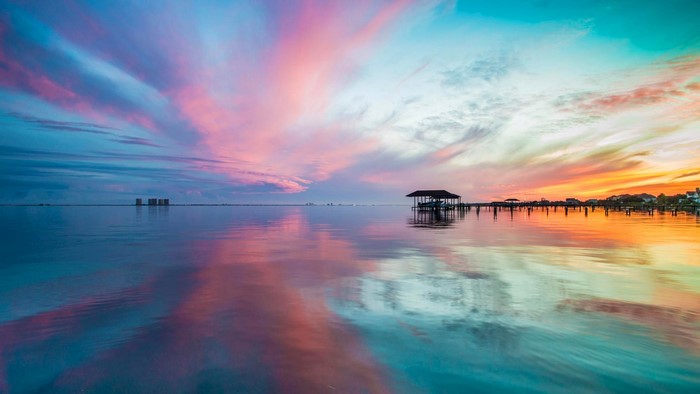 Sunset over the ocean with a pier and boathouse