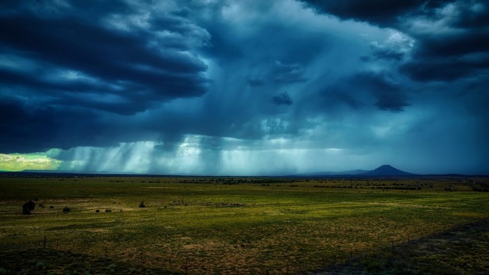 Stormy sky over a vast green field