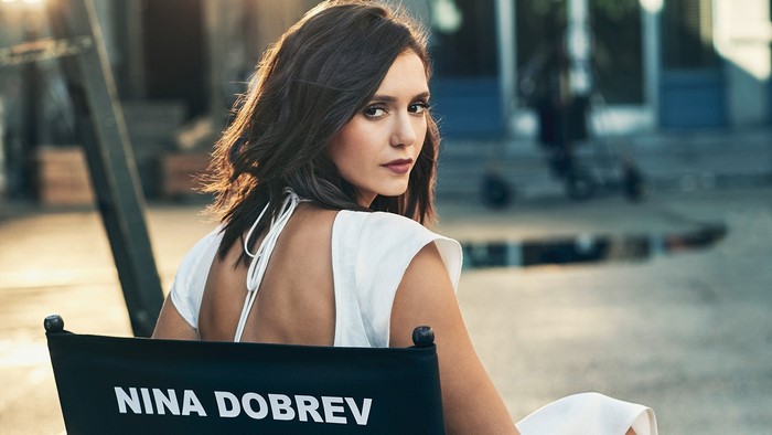 Nina Dobrev sitting on a director's chair