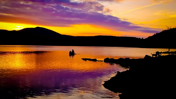 Sunset over a lake with a canoe and dogs