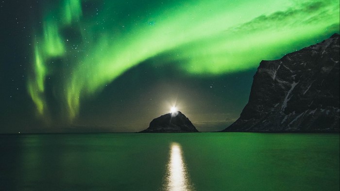 Northern Lights over the ocean with a lighthouse
