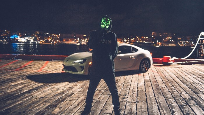 Person in Anonymous mask with car at night