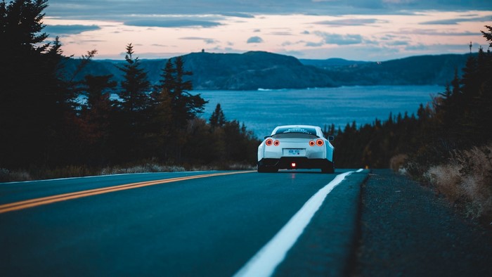 Nissan GT-R driving on a coastal road at dusk