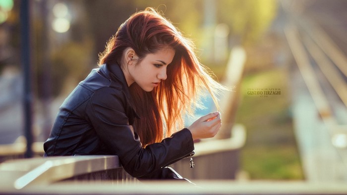 Woman with red hair leaning on a railing