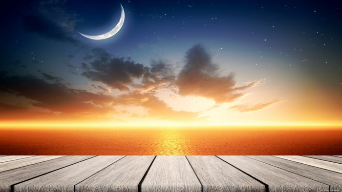 Sunset over the ocean with a crescent moon