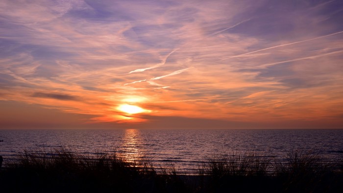 Sunset over the sea with clouds and grass