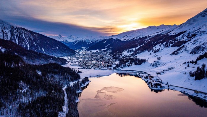 Snowy mountain valley with lake at sunset