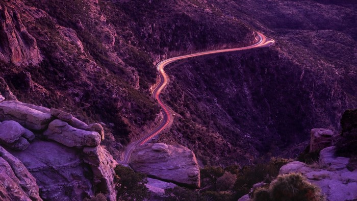 Winding mountain road with light trails at dusk